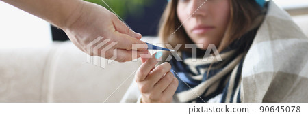 Someone give young woman thermometer to measure temperature 90645078