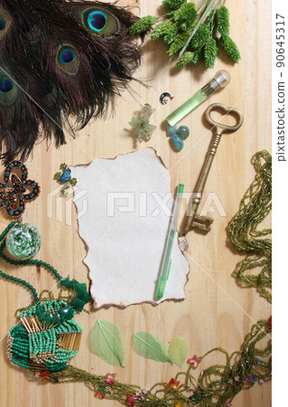 Vintage Burned Paper and Antique Key Surrounded By Green Jewelry and Peacock Feathers Vintage Burned Paper and Antique Key Surrounded By Green Jewelry and Peacock Feathers 90645317