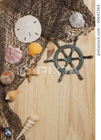 Captains Wheel With Fishing Net and Sea Shells on Wooden Background Captains Wheel With Fishing Net and Sea Shells on Wooden Background 90645364