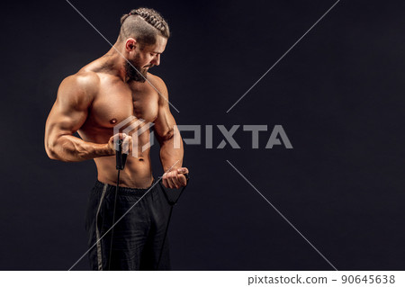 Muscular guy stretching rubber resistance bands in dark background 90645638