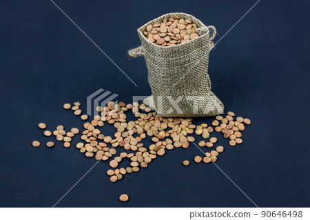 brown dried lentils in a burlap bag on black background 90646498