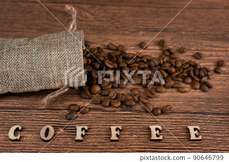 Black coffee foil packaging bag on wooden table top view. Spilled beans flat lay concept. Room for text.. 90646799