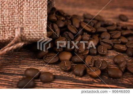 Black coffee foil packaging bag on wooden table top view. Spilled beans flat lay concept. Room for text. 90646800