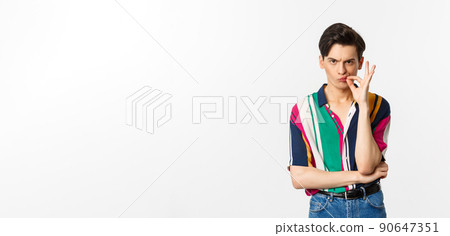 Sulking man zipping mouth, seal lips with promise, looking serious, standing over white background Sulking man zipping mouth, seal lips with promise, looking serious, standing over white background 90647351