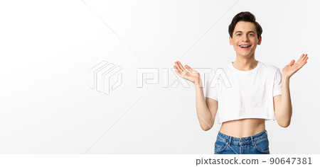 Lgbtq and pride concept. Happy and satisfied young gay man in crop top clapping hands proud, smiling at camera, standing over white background Lgbtq and pride concept. Happy and satisfied young gay man in crop top clapping hands proud, smiling at camera, standing over white background 90647381
