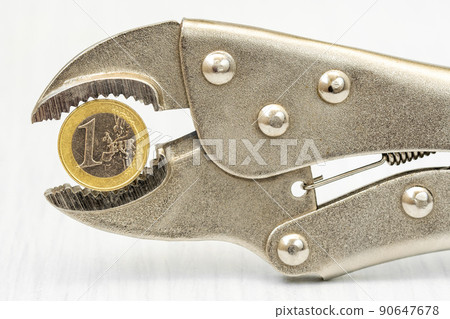 One euro coin squeezed in an adjustable wrench 90647678