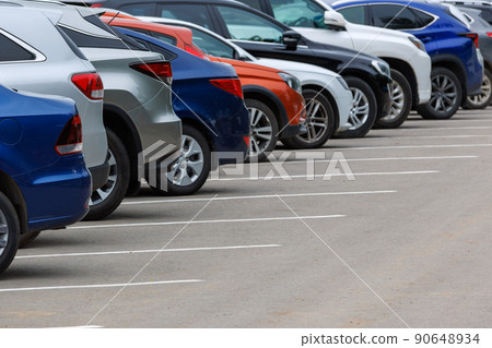 row of different color cars on asphalt parking lot at cloudy summer day 90648934