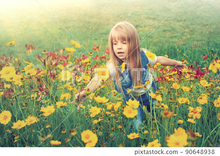 Little girl walking on flower lawn Little girl walking on flower lawn 90648938