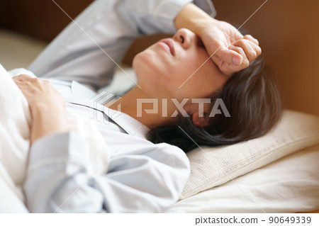 一個似乎難以入睡的中年婦女，一個躺在床上的女人 90649339