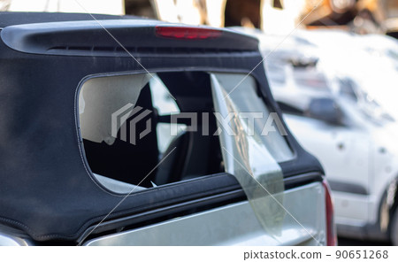 Damaged roof material on the back of the convertible. Vandalism, thieves cut the roof of a convertible from behind. Theft of things from the car. Criminal incident. Car burglary. 90651268