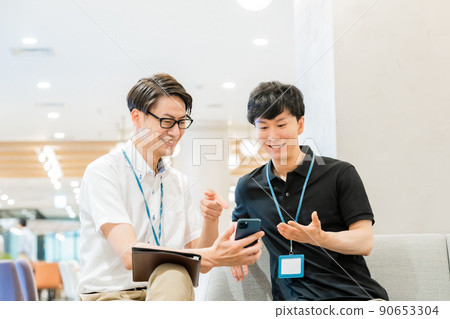 A businessman looking at a smartphone with two people 90653304