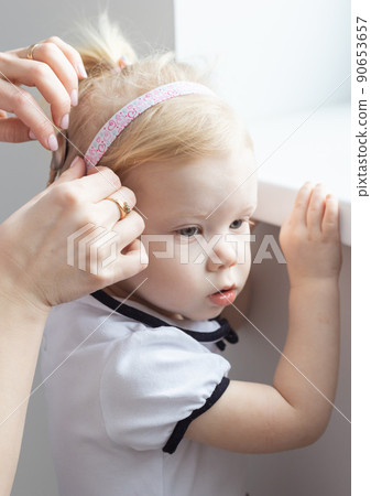 Mother fixing her daughter's cochlear implant hearing aid - deafness and diversity concept. Innovative technologies in treatment of deafness 90653657