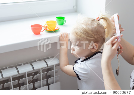Mother fixing her daughter's cochlear implant hearing aid - deafness and diversity concept. Innovative technologies in treatment of deafness Mother fixing her daughter's cochlear implant hearing aid - deafness and diversity concept. Innovative technologies in treatment of deafness 90653677