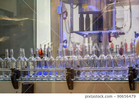 Glass empty bottles on the automatic conveyor line at the wine factory. Winery. Plant for bottling alcoholic beverages. Industrial production line unmanned operation cork sealing Glass empty bottles on the automatic conveyor line at the wine factory. Winery. Plant for bottling alcoholic beverages. Industrial production line unmanned operation cork sealing 90656479