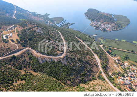 Meandering serpentine road in the mountain with lake and small islad. Aerial view. Copter, drone view Meandering serpentine road in the mountain with lake and small islad. Aerial view. Copter, drone view 90656698