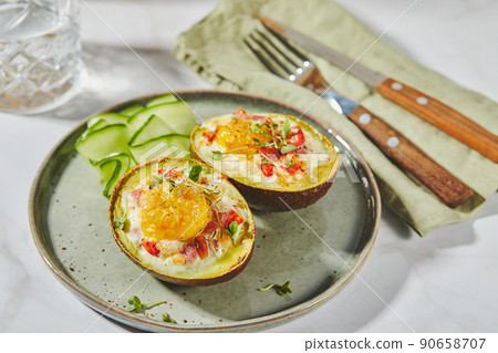 Avocado baked with egg, ham, tomatoes and cheese. Keto lunch recipe. After baking Avocado baked with egg, ham, tomatoes and cheese. Keto lunch recipe. After baking 90658707