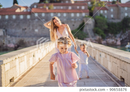 Mother and two children daughter and son tourists on background of beautiful view St. Stephen island, Sveti Stefan on the Budva Riviera, Budva, Montenegro. Travel to Montenegro concept 90658876