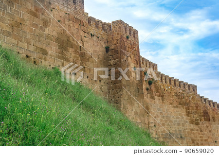 wall of a medieval fortress above a rampart overgrown with grass against the sky, Naryn-Kala citadel in Derbent 90659020