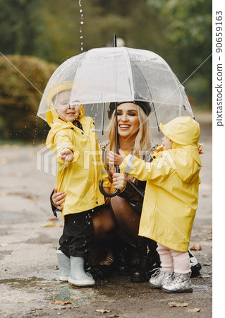 Family in a rainy park. Kids in a raincoats. Mother with child. Woman in a black coat. Family in a rainy park. Kids in a raincoats. Mother with child. Woman in a black coat. 90659163