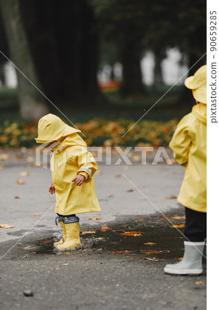 Kids in a autumn park. Children in a yellow raincoats. People having fun outdoors. Kids in a autumn park. Children in a yellow raincoats. People having fun outdoors. 90659285