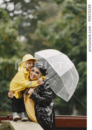 Family in a rainy park. Kids in a raincoats. Mother with child. Woman in a black coat. Family in a rainy park. Kids in a raincoats. Mother with child. Woman in a black coat. 90659286