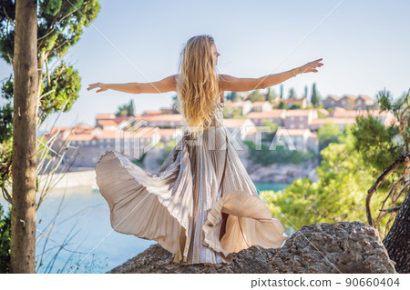 Woman tourist on background of beautiful view of the island of St. Stephen, Sveti Stefan on the Budva Riviera, Budva, Montenegro. Travel to Montenegro concept Woman tourist on background of beautiful view of the island of St. Stephen, Sveti Stefan on the Budva Riviera, Budva, Montenegro. Travel to Montenegro concept 90660404