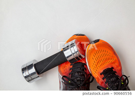 Metal dumbbell fell on the feet of an athlete in orange sneakers. Safety precautions when training with heavy equipment 90660556
