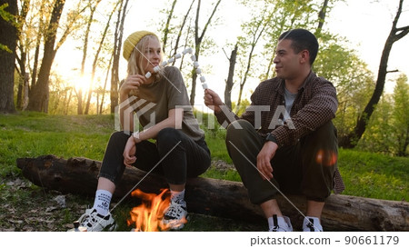 Camping and picnic concept. romantic couple frying marshmallow on fire in forest and eating it Letters on soks mean RUSSIAN WARSHIP GO FUCK Camping and picnic concept. romantic couple frying marshmallow on fire in forest and eating it Letters on soks mean RUSSIAN WARSHIP GO FUCK 90661179