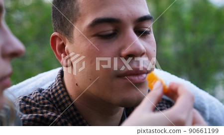 Woman feed a man with orage peace in the forest camping. Love story outdoor. Woman feed a man with orage peace in the forest camping. Love story outdoor. 90661199