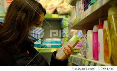 Woman choosing chemistry and self care products at a household goods in the store in mask Woman choosing chemistry and self care products at a household goods in the store in mask 90661230