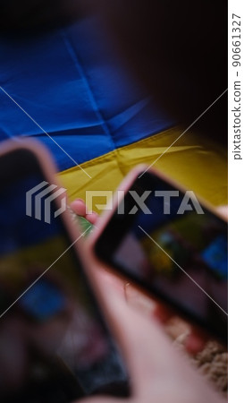 The national flag of Ukraine as a background. Girls, womens with phone in the hands peace in Ukraine, no war, free country, peace in Ukraine The national flag of Ukraine as a background. Girls, womens with phone in the hands peace in Ukraine, no war, free country, peace in Ukraine 90661327