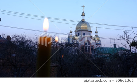 blured burning candle wit a church on background with the stained-glass windows Location 90661365