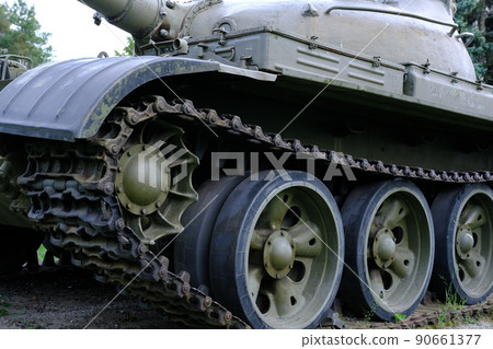 view of the front part of the green caterpillar of the tank standing on the ground with the wheels close-up 90661377