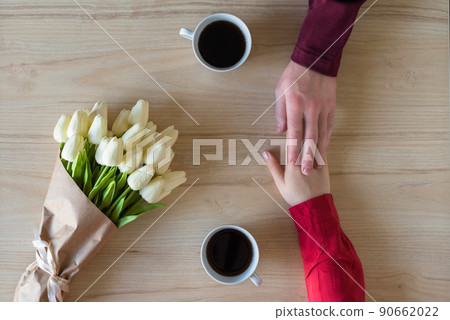 Valentines day. Close-up of woman and man celebrating in restaurant. Boyfriend giving bouquet of tulips to girlfriend. love, romance, date. Flat lay Valentines day. Close-up of woman and man celebrating in restaurant. Boyfriend giving bouquet of tulips to girlfriend. love, romance, date. Flat lay 90662022