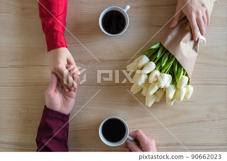 Valentines day. Close-up of woman and man celebrating in restaurant. Boyfriend giving bouquet of tulips to girlfriend. love, romance, date. Flat lay Valentines day. Close-up of woman and man celebrating in restaurant. Boyfriend giving bouquet of tulips to girlfriend. love, romance, date. Flat lay 90662023