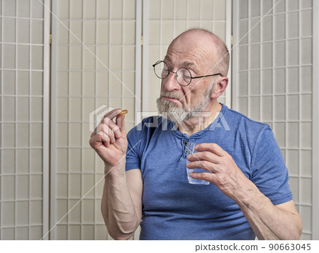 senior man is taking a medicine or supplement pill 90663045