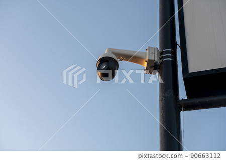CCTV camera mounted on a tall black pole. Surveillance camera with all-round view. CCTV camera mounted on a tall black pole. Surveillance camera with all-round view. 90663112