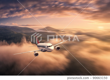 Airplane is flying above the clouds at sunset in summer 90663150
