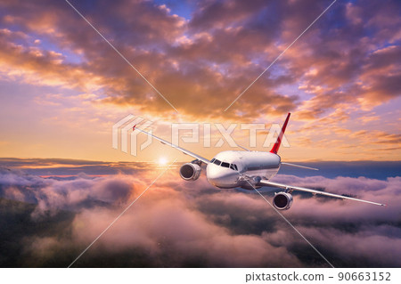 Airplane is flying above the clouds at sunset in summer 90663152