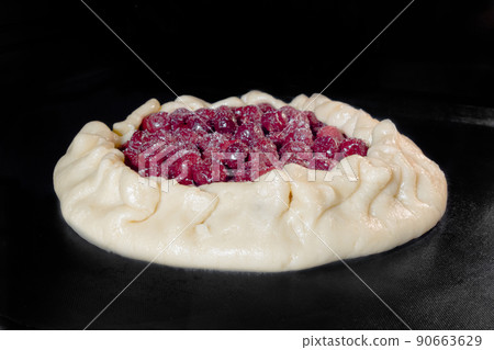 Uncooked homemade galette, open pie with cherry baking in electric oven 90663629