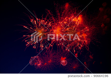 Bright red sparks come from the center of the fireworks, next to it smoke on the background of the night sky. High quality photo 90664196