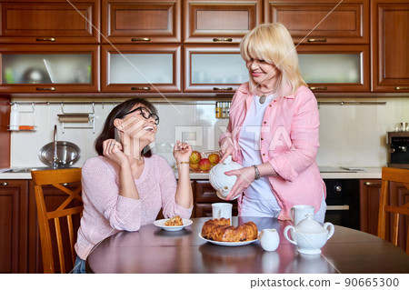 Two smiling happy mature women girlfriends in the kitchen together 90665300