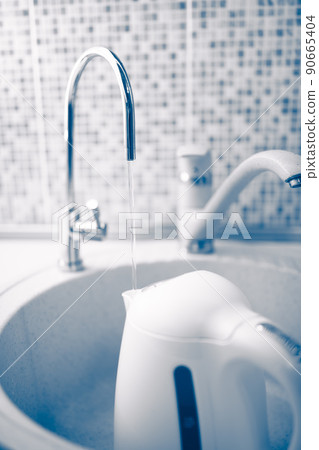 kettle pouring with fresh purified water under a filter tap 90665404