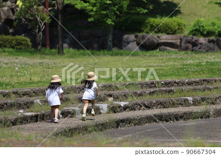 在埼玉縣鳩山町綠意盎然的鄉村公園裡，喜歡在石階上跑步和玩耍的戴著草帽的小妹妹。 90667304