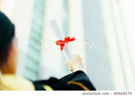 Happy Asian graduate student holding the diplomas on hand during the university graduation ceremony. Master degree student in gown suit holding a diplomas for photography. Happy Asian graduate student holding the diplomas on hand during the university graduation ceremony. Master degree student in gown suit holding a diplomas for photography. 90669279