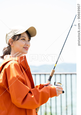 一個微笑的年輕女子在藍天下享受釣魚作為一種愛好 90669907