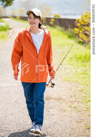 一位微笑的年輕女子在藍天下快樂地行走時尋找釣魚點 90669930
