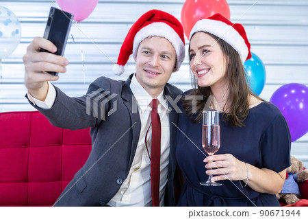 Happy new year 2022 concept, Selfie of Happy couple holding the champagne glass in Christmas and New Year's Eve party Christmas tree background After finishing business work Happy new year 2022 concept, Selfie of Happy couple holding the champagne glass in Christmas and New Year's Eve party Christmas tree background After finishing business work 90671944