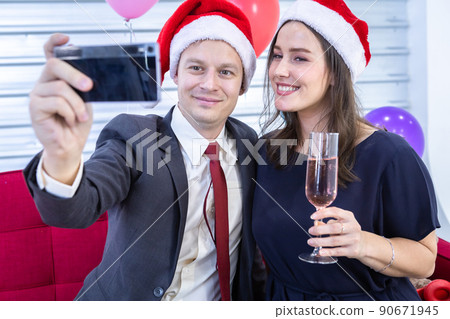 Happy new year 2022 concept,Selfie on smartphone of Happy couple holding the champagne glass in Christmas and New Year's Eve party Christmas tree background After finishing business work Happy new year 2022 concept,Selfie on smartphone of Happy couple holding the champagne glass in Christmas and New Year's Eve party Christmas tree background After finishing business work 90671945