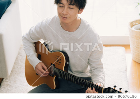 A man playing the guitar in the living room 90676186